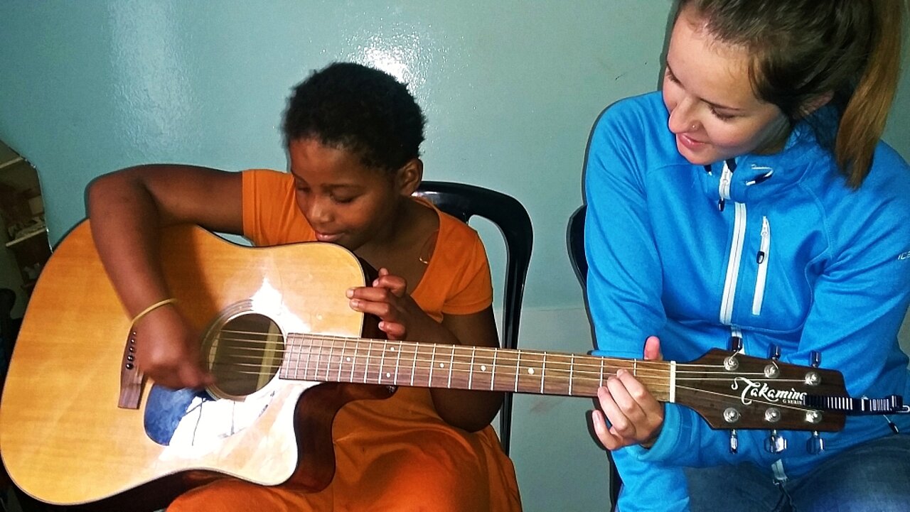Unsere Freiwillige Ellen gibt einem südafrikanischen Jungen Gitarrenunterricht.