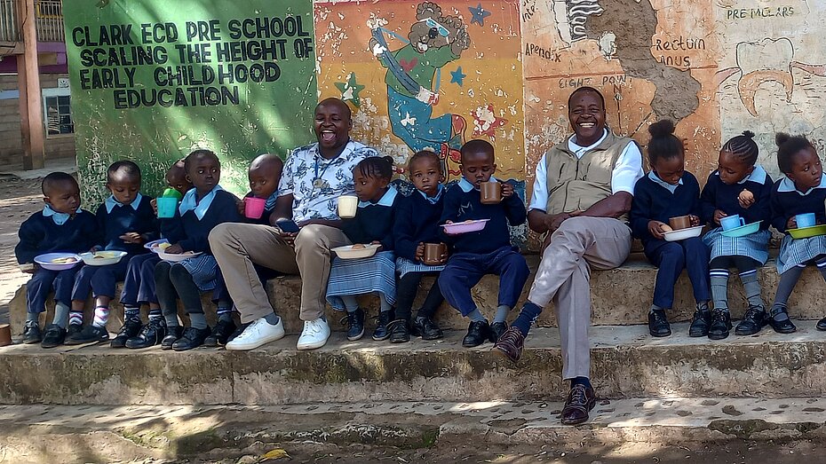 Kinder und Lehrkräfte essen im Freien in einer Schule in Athiru Gaiti, Kenia.